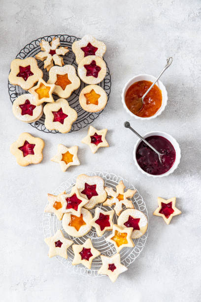 biscotti natalizi tradizionali linzer ripieni di marmellata di mirtilli rossi e marmellata di arance su sfondo di legno - marmalade baked biscuit brown foto e immagini stock