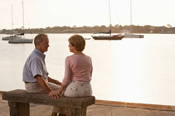 Senior couple sitting on waterfront Senior couple sitting on bench by waterfront. Sc0560 stock pictures, royalty-free photos & images
