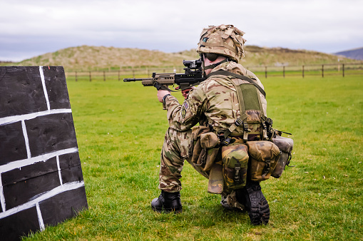 Magilligan Army Training Grounds, Londonderry, Northern Ireland, UK. 05/04/2014 - A soldier from the 2 Royal Irish Regiment (reserves, formerly the Territorial Army) of the British Army takes aim from a kneeling position at a target 75m away while he trains on a military firing range with an SA80 assault rifle. The Royal Irish Regiment is a light infantry brigade of the British Army specialising in forward operations, close combat, artillery forward observation, light mechanised duties and logistics.  Soldiers take part in regular training exercises at Magilligan or Ballyhornan in Northern Ireland in conjunction with other Northern Ireland based regiments such as the Royal Artillery, the Scottish and North Irish Yeomanry, Royal Signals and the Royal Armoured Medical Corp.