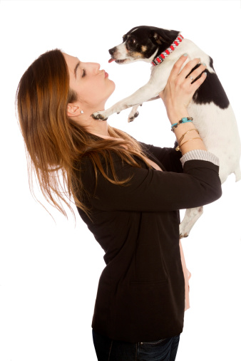 young woman holds dog from profile, making kiss face, while dog sticks out toungue