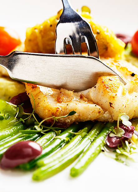 istock Knife and fork slicing into grilled fish dish at restaurant 175242260