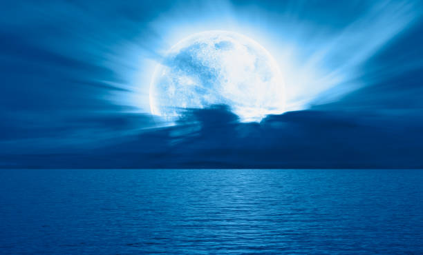 istock Night sky with blue moon in the clouds over the calm blue sea 