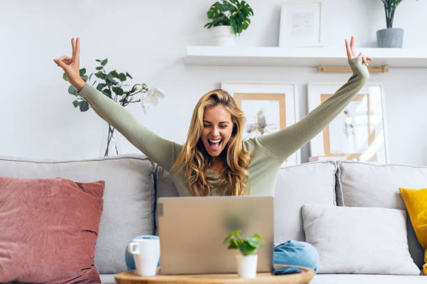 istock Pretty motivated woman celebrating something while working with laptop sitting on a couch at home 1752441613