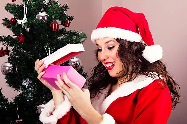 Pretty Mrs.Claus opening gift box and smiling
