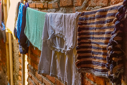 Clothesline in a small alley with a brick wall in the background. A densely populated area.