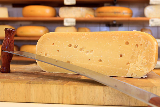 cutted cheese on a wooden cutting board with a special cheese cutter in the foreground