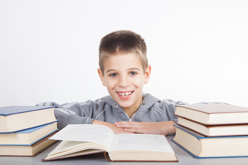 Smiling kid between the stacks of books. Education, back to school concept