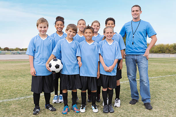 Youth league soccer team posing with coach before game