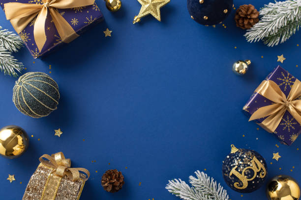 istock Gift Elegance. Overhead image featuring sparkling blue and gold-wrapped gifts, ornaments, radiant star, glitter, pinecones, frosty evergreen branches against rich blue backdrop for greeting or advert 1752468406