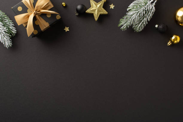 istock Elegant Yuletide dreams theme. Top view of sumptuous gift parcels, expensive tree balls, shimmering star, twinkling confetti, frost-covered evergreen sprigs against dark backdrop for your festive text 1752469495