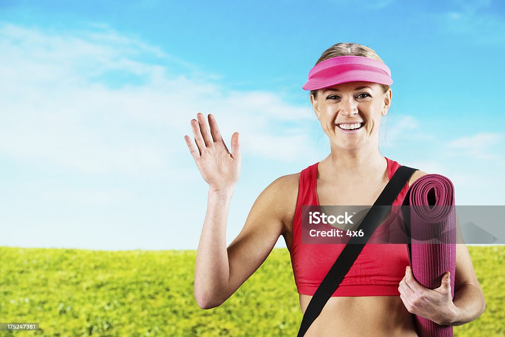 Sonriente mujer agarrando una estera de yoga - Foto de stock de 20 a 29 años libre de derechos