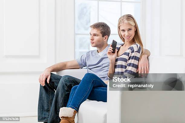 Caucasiana Jovem Casal Sentado No Sofá Segurando O Controlo Remoto - Fotografias de stock e mais imagens de 20-24 Anos
