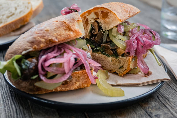 istock Delightful lunch break with a Ciabatta bread adorned with pickled red onions, roasted mushrooms, mustard pickled gherkins and Cambozola cheese, a sensory pleasure on a rustic table, ready to eat. 1752477038