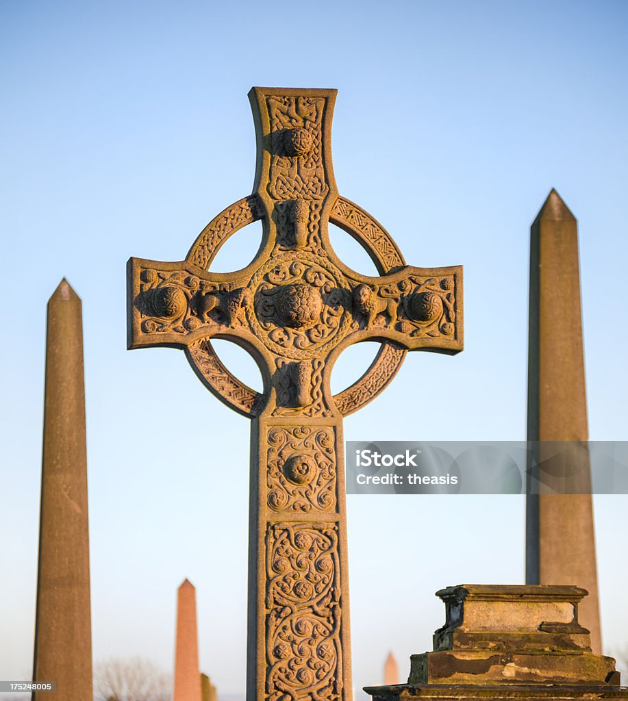 Celtic Cross A granite celtic cross gravestone in Glasgow's Necropolis cemetery against a blue dusk sky. Blue Stock Photo