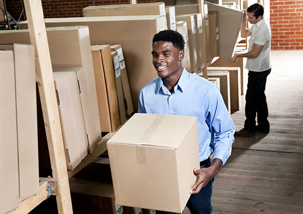 African American male carrying box in a storage room stock photo