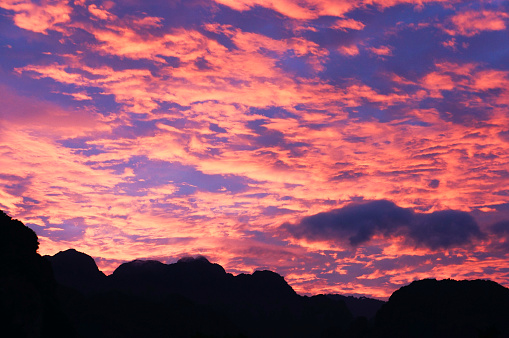 Experience the enchanting allure of Vang Vieng, Laos, as the sun sets behind the iconic karstic mountains, painting the sky in mesmerizing shades of pink and blue. This breathtaking moment captures the tranquil and ethereal ambiance of this Southeast Asian gem, framed by the silhouettes of the dramatic karstic formations.