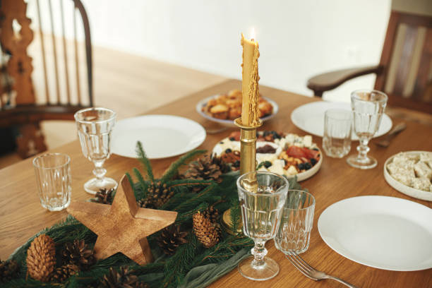 istock Christmas table setting. Stylish table runner with fir branches and pine cones, candles, cheese appetizers and starters, glasses and cutlery. Holiday dinner arrangement. Happy new year! 1752504053