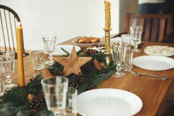 istock Christmas table setting. Stylish table runner with fir branches and pine cones, candles, cheese appetizers and starters, glasses and cutlery. Holiday dinner arrangement. Happy new year! 1752504073