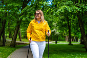 Mid adult woman exercising Nordic walking in city park