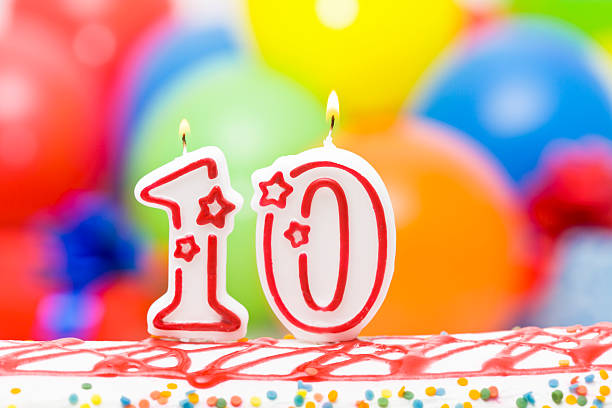 Cake for tenth birthday Cake for 10th birthday with lighted candles. Balloons in background. 10 11 years photos stock pictures, royalty-free photos & images