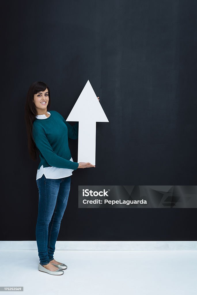 Woman pointing up Young woman holding a white arrow and pointing up. 20-24 Years Stock Photo