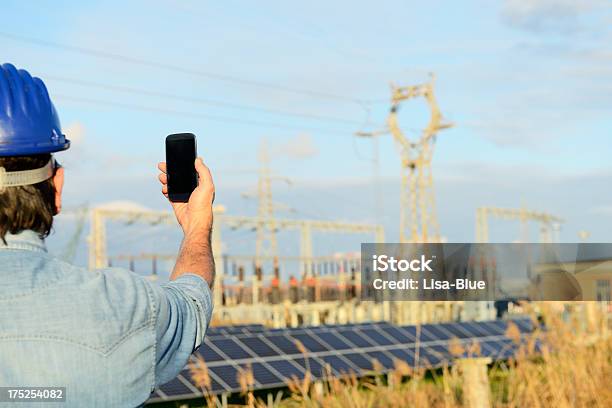 Ingegnere Con Smart Phone In Un Impianto Di Energia Solare - Fotografie stock e altre immagini di Elmetto da cantiere