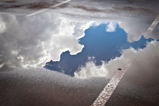 Puddle with sky and clouds, parking lot after storm, California.