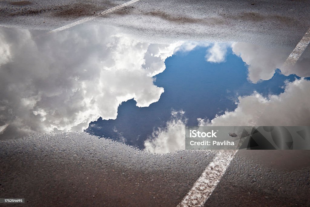 Sky with Clouds Reflected in a Puddle Puddle with sky and clouds, parking lot after storm, California. Puddle Stock Photo