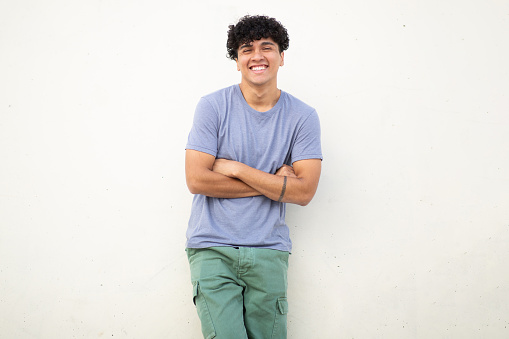 Portrait cool guy smiling against white wall with arms crossed