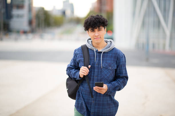 istock Young man standing in city with mobile phone and bag 1752554513