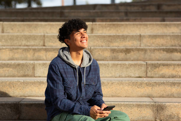 istock smiling young man sitting on steps with mobile phone 1752555268