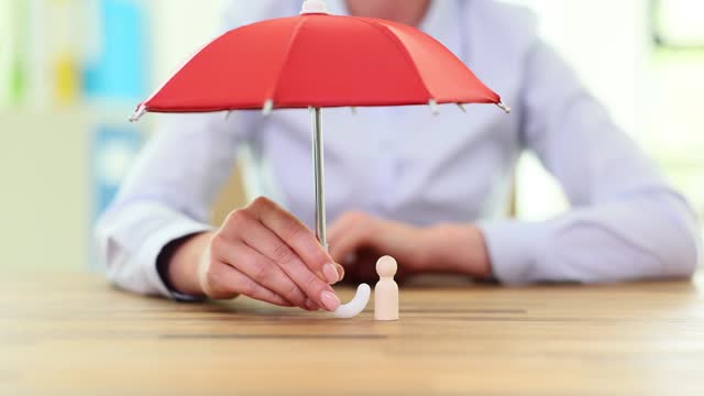 Female holding big red umbrella above wooden human figure