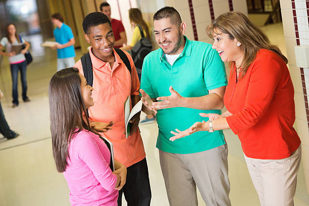 istock High school students talking with teachers after class in hallway 175256450