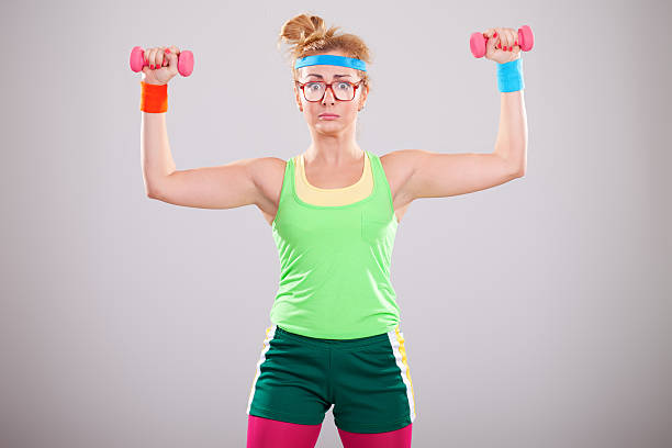 Clumsy looking nerdy woman lifting small pink weights Portrait of strong female geek working with weightsYOU ARE WELCOME TO VISIT SOME OF MY MANAGED LIGHTBOXES blonde female bodybuilders stock pictures, royalty-free photos & images