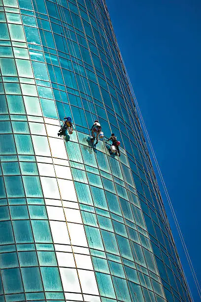 "skyscraper window facade climbing cleaning crew try to clean the desert sand of doha, capital city of qatar, arabian gulf."