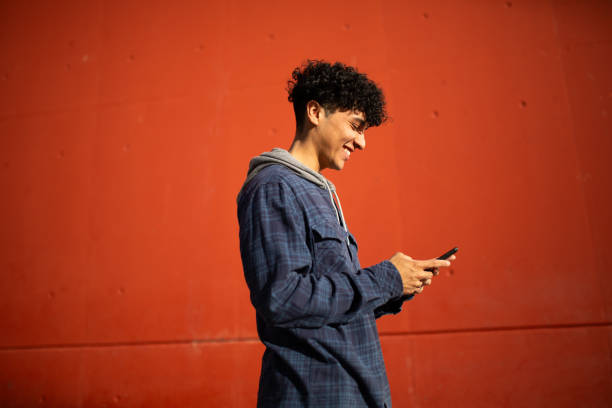 istock Profile smiling young man with cellphone by red wall 1752573944