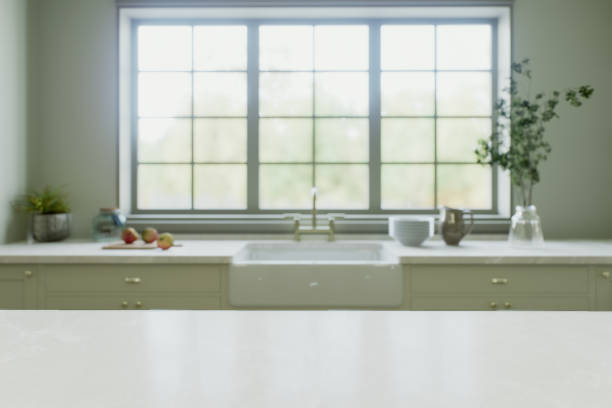 istock Kitchen interior with an island with a white stone countertop - for placing and advertising products against the blurred background of the kitchen by the window. 3D rendering 1752575676