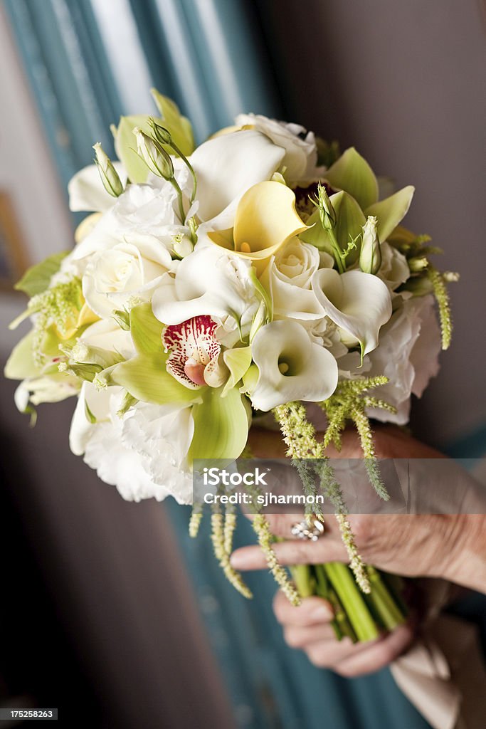 Classic Wedding Bridal Bouquet of Calla Lilies, Orchids, and Roses "A woman is holding a gorgeous bridal bouquet of white roses, calla lilies, and orchids." Arrangement Stock Photo