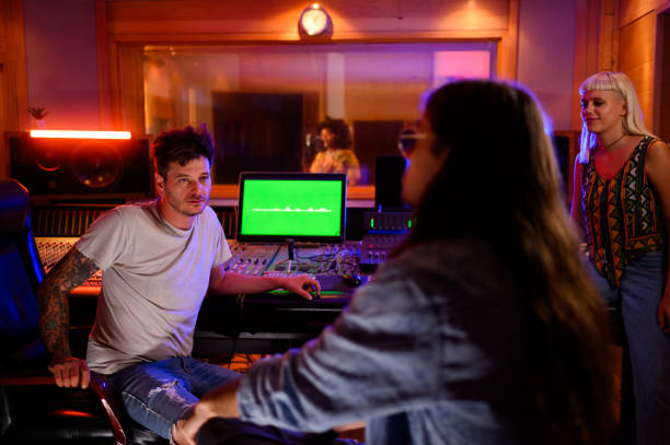 istock Band mates talking in a music studio while vocalist is recording her part. 1752586285