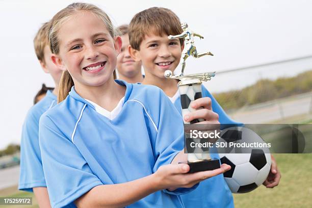 Photo libre de droit de Heureuse Petite Fille Tenant Un Trophée De Football Après Avoir Remporté Match banque d'images et plus d'images libres de droit de Petites filles