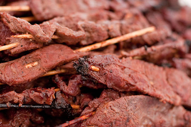 A pile of char broiled beef skewers with wooden skewers for an appetizer.