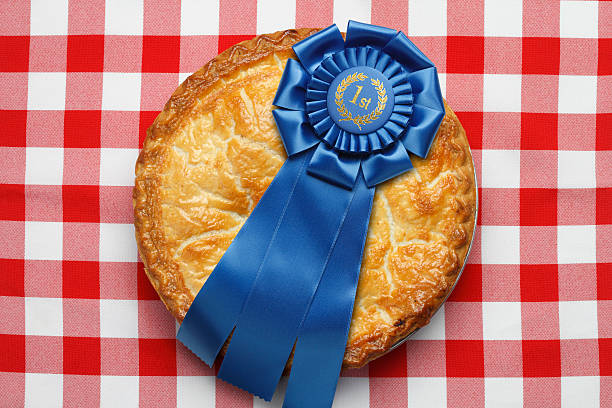 First place ribbon on pie sitting on red checkerboard tablecloth A pie with a blue first place ribbon on top.  The pie is sitting on a classic red checkerboard tablecloth. Image evokes the feeling of classic Americana. Camera angle is from directly above. agricultural fair photos stock pictures, royalty-free photos & images