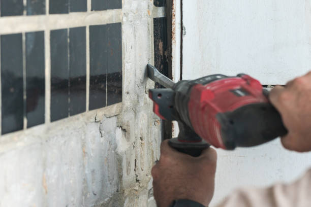 istock Builder with a puncher dismantles old tiles from a concrete wall 1752604624