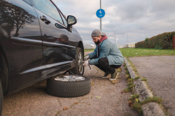 istock Young man unscrewing his car tires outdoors before replacing them 1752605775