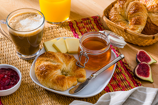 Sweet breakfast of croissant and honey . Coffee, orange juice and fruits
