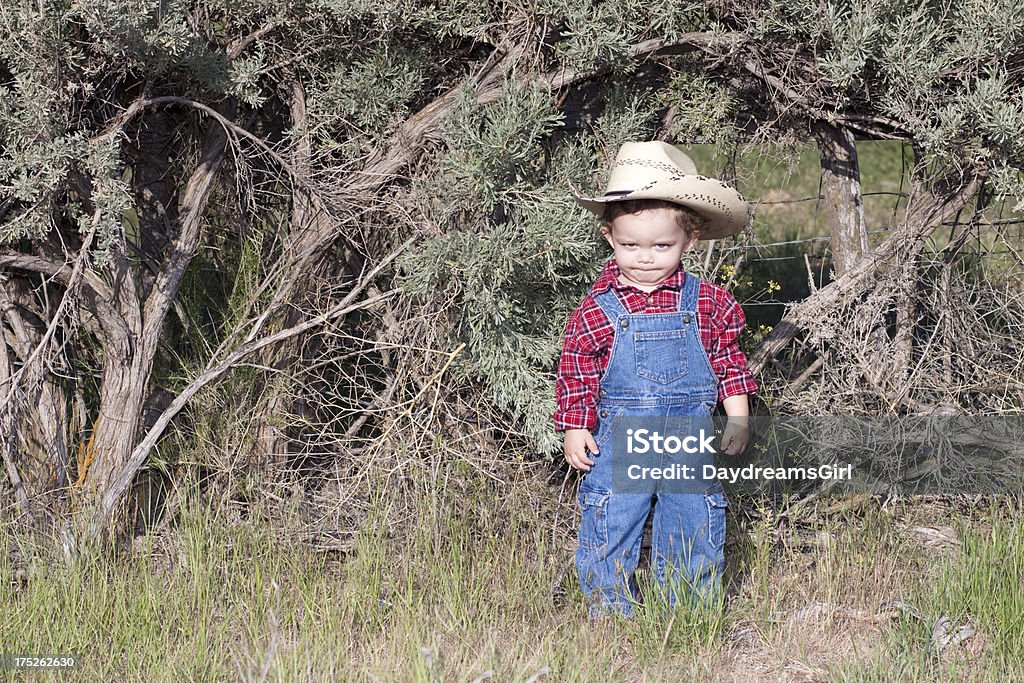 Angry menino em Blue Denim macacão usando chapéu de caubói - Foto de stock de 12-17 meses royalty-free