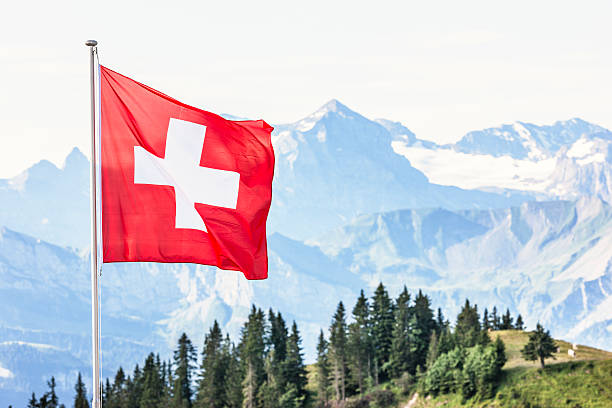Swiss flag flying in alpine landscape Swiss national flag fluttering in a light summer breeze. AdobeRGB colorspace. Other views around Lake Lucerne: swiss flag photos stock pictures, royalty-free photos & images