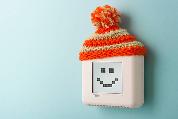 Digital room temperature thermostat with smiley face and wooly hat stock photo