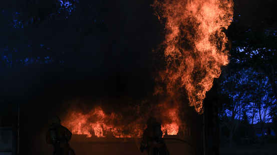 Two Firefighters practice to close the frame of fire and smoke from inside of the closed room