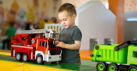 Cute toddler boy playing with cars in children's playroom. Active lifestyle, childhood. Selective focus
